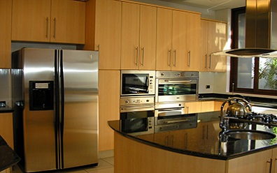 Proyecto de Muebles de cocina94 con puertas Lamitech Abedul y cubierta de granito verde Ubatuba, manillas de acero inoxidable en La Dehesa comuna de Lo Barnechea